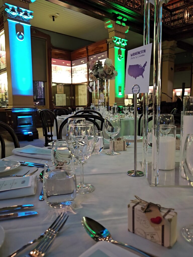 Romantic table setting with “Washington” table sign, floral centerpiece, and guest favor inside Mortlock Chamber, State Library of South Australia. Heritage-listed venue available for events and weddings through Australian Hiring Company.