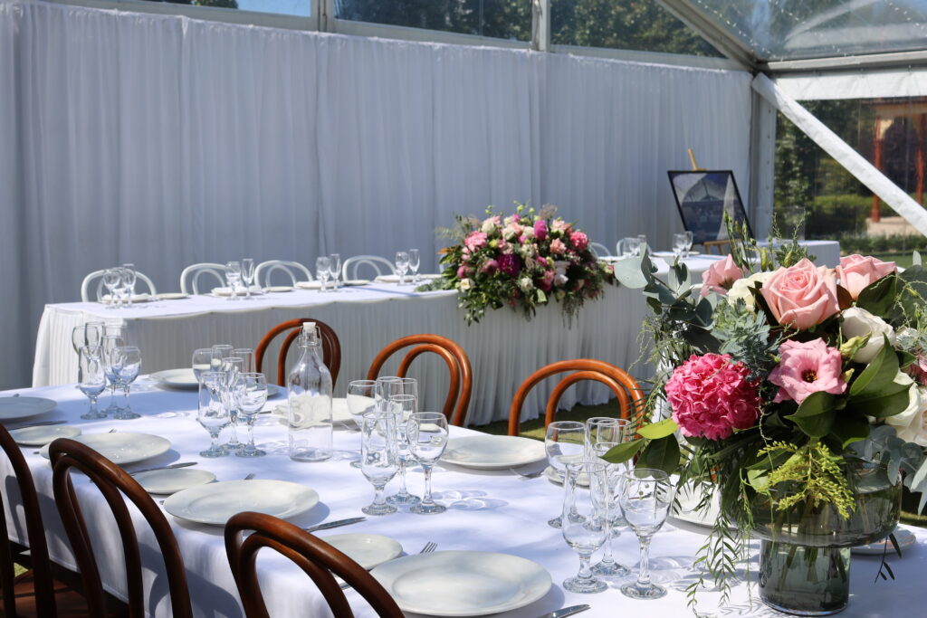 Party Hire Adelaide - Elegant wedding reception setup under a transparent marquee with floral centerpieces and formal table settings—available from Australian Hiring Company in Adelaide.