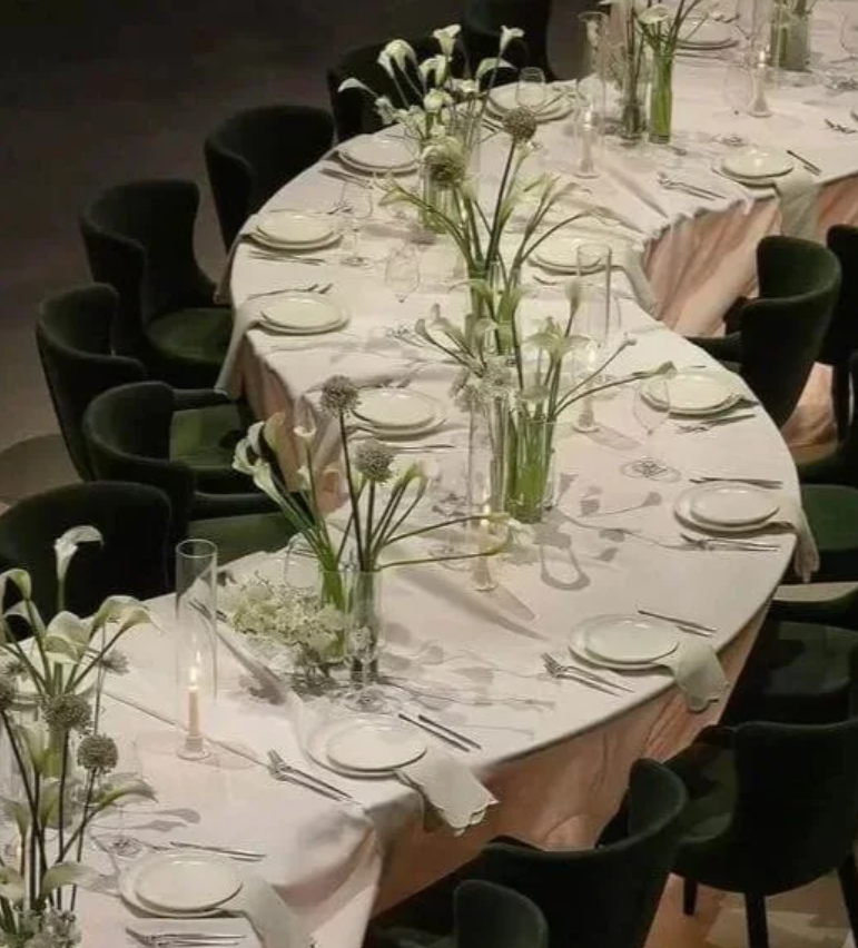 Elegant serpentine dining tables with white linens, green upholstered chairs, and tall white floral arrangements, supplied by Australian Hiring Company in Adelaide with event coordination and installation by AHC+ Events.